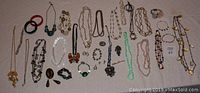 Photo showing assorted vintage costume jewelry spread on a surface including necklaces, bracelets, pins, and brooches, some marked and a Russian set.