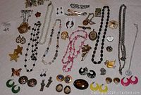 Full view of assorted vintage costume jewelry spread out on a cloth with distinct pieces visible