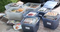 Multiple plastic bins filled with numerous food and cooking magazines with some issues stacked outside the bins.