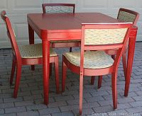 Photo showing the Art Deco table surrounded by 4 red chairs with alligator print upholstery, highlighting overall condition and design.