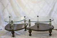 Front view of the two boomerang-shaped tables showing glass tops and faux marble bottoms with metal carved legs.