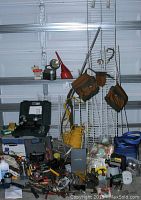 Wide view showing assorted tools, wire shelving panels, extension cords, and equipment on garage floor and shelves.