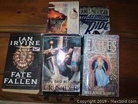 Top view of five assorted novels by various authors arranged on a wooden surface.