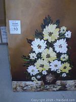 Front view of flower painting on canvas showing bouquet of white and cream flowers with green leaves on a brown background.
