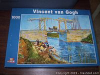 Box front showing Vincent van Gogh puzzle image with a bridge over a body of water and people in boats.