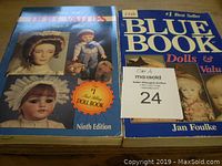 Two doll value books placed side by side on a table. The books are 'Doll Values Ninth Edition' and 'Blue Book Dolls & Values' by Jan Foulke.
