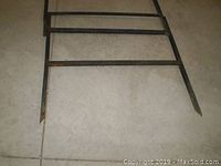 Photo showing one black metal sign frame with horizontal bars and pointed ends for ground placement.