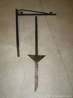 Photo of the two metal bracket holder pieces on a concrete floor, showing the full lengths and the ground spike element.