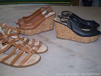Three pairs of women's shoes: brown leather cork wedge sandals, black leather cork wedge sandals, and brown flat gladiator-style sandals, all on a wooden surface.