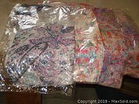 Four ladies scarves still in unopened plastic packaging, laid out to show different patterns and colors
