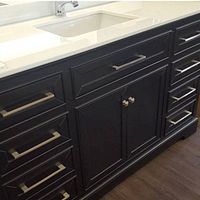 Front view of black vanity cabinet with white quartz countertop and integrated sink