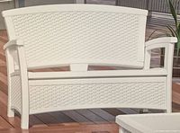 White Suncast resin loveseat with woven textured pattern and sturdy armrests.