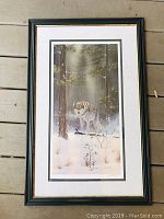 Framed print of a wolf standing in a snowy forest with pine trees.