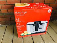 Box of GE deep fryer with 5 liter capacity on wooden floor, red box showing product image and brand.