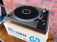 Pioneer PL-112D turntable on original box showing top platter, tonearm and controls.