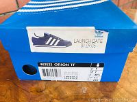 Blue Adidas box front with 'Orion TF' label, size and launch date info