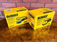 Photo showing two DeWalt sanders in their original yellow boxes with model numbers DW421 and DW411 indicated on packaging.