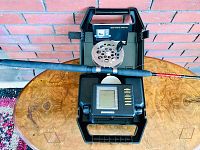 Photo shows open Humminbird fish finder unit with screen and control panel, fishing rod and reel placed on table.