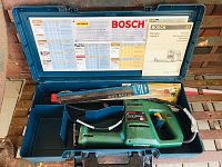 Photo of blue plastic case containing Bosch PFZ 550 E electric saw, various blades and operator manuals inside case lid.