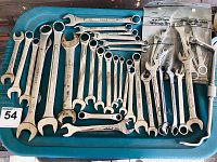 View of large collection of wrenches of multiple sizes laid on a green tray, includes open and box end sizes, some in packaging