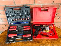 Open view of electric soldering gun, solder wire spool, and solder tip cleaner in red plastic case.