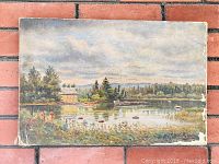 Full view of the oil painting showing the lakeside scene with a cabin, trees, boats, and a cloudy sky; worn edges visible.