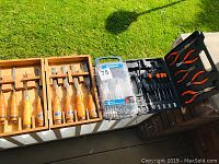 Overall view of tools including chisels in wooden cases, drill bit set, pliers, and screwdrivers.
