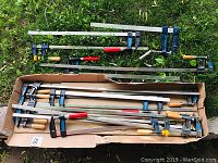 Two loose clamps on grass and a cardboard tray holding multiple clamps