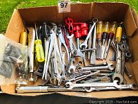 Top view of box filled with assorted wrenches, pliers, screwdrivers, and other hand tools.