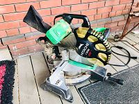 View of the entire mitre saw showing green motor casing, black blade guard with yellow details, and base with adjustable angle scale.