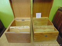 Two vintage wooden dovetail file drawer boxes with hinged lids open, showing internal alphabetical file dividers, placed side by side on green background.