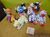 Photo showing 10 TY Beanie Babies including a cream dog, colorful dog, and several patriotic star-spangled dogs and bears with tags.