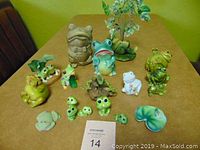 Overview of all frog figurines on table showing variety of sizes and materials