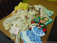 Photo of assorted vintage crochet items including doilies, placemats, and decorative items in various colors spread on a surface