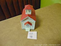 Front view of the ceramic schoolhouse cookie jar showing the chimney, front door with awning, and window above door.
