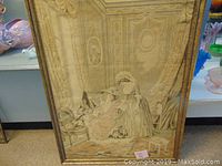 Framed tapestry measuring 26 by 36 inches showing two women and a dog in a detailed interior setting with decorative panels and curtains.