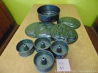 Photo of six springform pans on table including one larger 9-inch pan and five 4-inch pans with various shapes