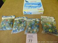 Four bags of colorful assorted arcade marbles arranged in front of Herpa airplane model box