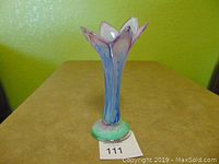 Art glass vase on table with green wall background, showing flared petal top and multicolor design