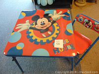 Child's square table with blue metal legs and colorful Mickey Mouse graphic on the surface.
