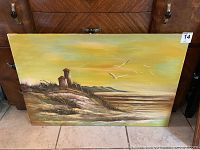 Full view of the 24x36 unframed painting showing the beach scenery with two rustic buildings, shoreline, and seagulls in flight.