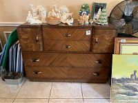 Front view of vintage wooden dresser with various decorative items displayed on top including nativity figurines and holiday houses. Shows drawer and cabinet layout, handles, and overall finish.