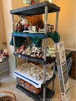 Full view of the black and gray plastic shelving with multiple shelves and vertical support posts. Shelves display various items and the unit is free standing.