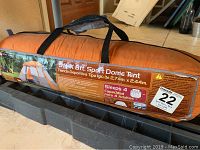 Photo of the orange carrying bag with printed tent dimensions and features along with Maxsold sticker.