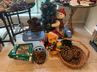 Overall view of Christmas decorations showing snowman, Winnie the Pooh, basket with pine cones, small decorated tree, and tree top star light in box.