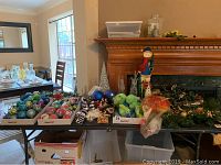 Wide shot of assortment of Christmas decorations on tables and mantle including baubles, wreaths, and figurines