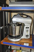 Full view of Farberware stand mixer on shelf with stainless steel mixing bowl installed.