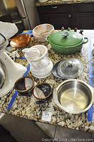 Kitchen counter with green Le Creuset cast iron pot, white GTC juicer, ceramic bowls, duck figurines, and decorative bowls including copper, glass, and stainless steel bowls.