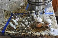 Top view of various salt and pepper shakers on a kitchen counter showing different designs including birds and metal tops