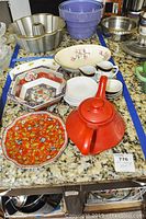 Wide view of bowls, plates, creamers, teapot, and bundt pan on countertop.